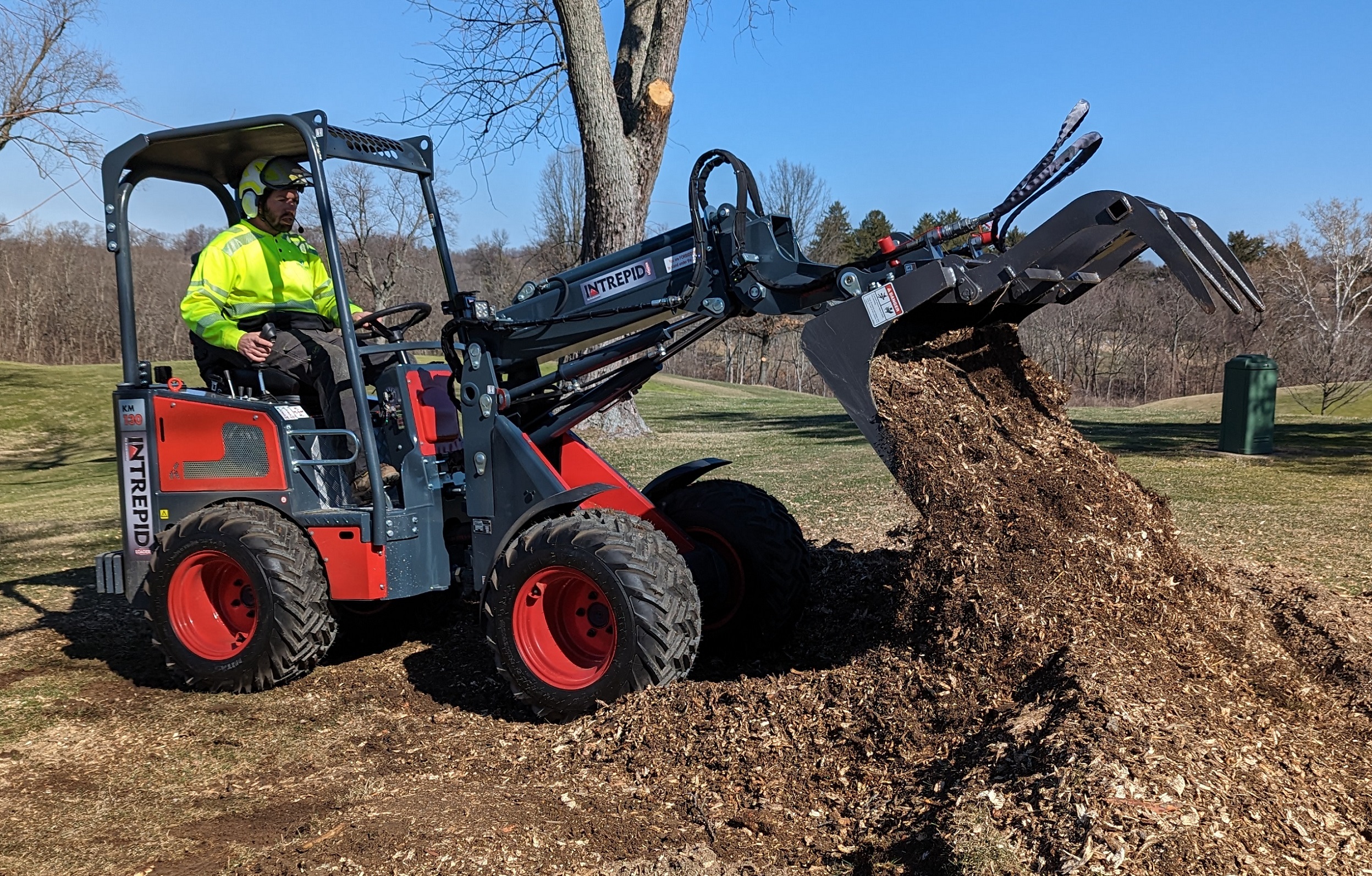 Compact wheel loader with grapple bucket moving mulch