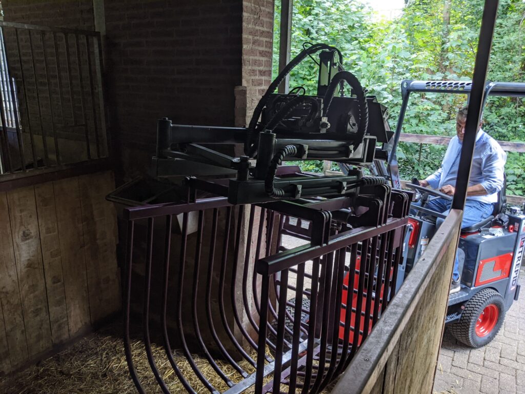 Purple packer loader cleaning horse stall